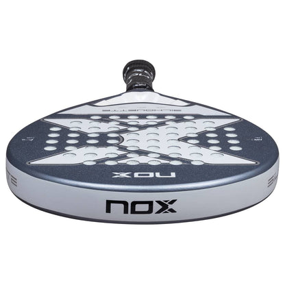 A close-up of the NOX X-One Silhouette 2026 Padel Racket highlights its round head, gray and white design, multiple holes, and "NOX" branding—making it an ideal choice for beginner players.